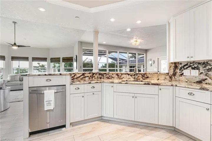 Kitchen with a textured ceiling, stainless steel dishwasher, open floor plan, recessed lighting, and light stone counters