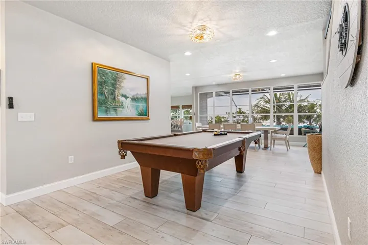 Recreation room with a textured wall, a textured ceiling, light wood-style flooring, pool table, and healthy amount of natural light
