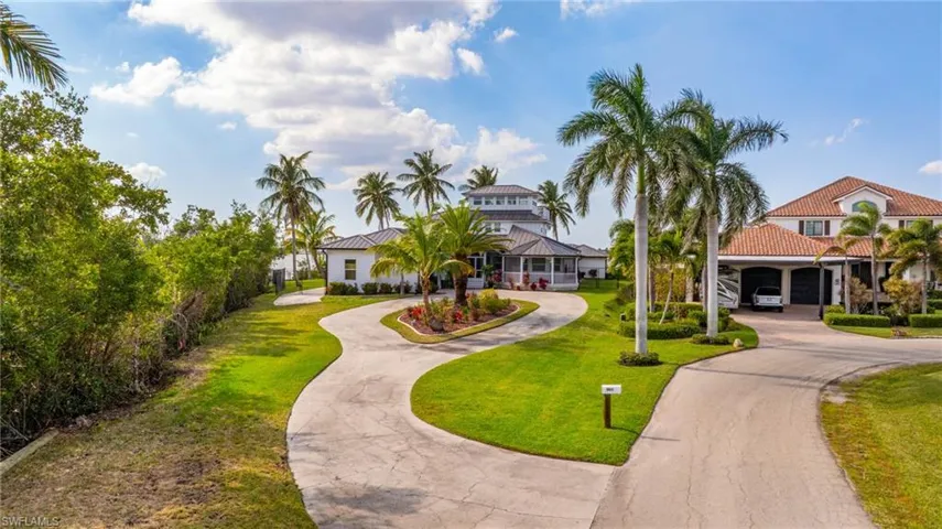 View of property's community with curved driveway and a lawn