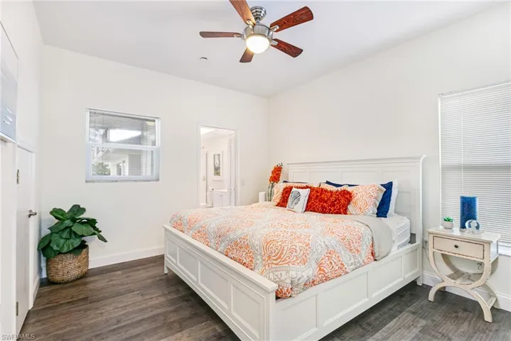 Bedroom with dark wood-style flooring, a ceiling fan, and ensuite bathroom
