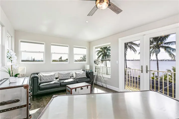Living room with a water view, french doors, dark wood-type flooring, and a ceiling fan