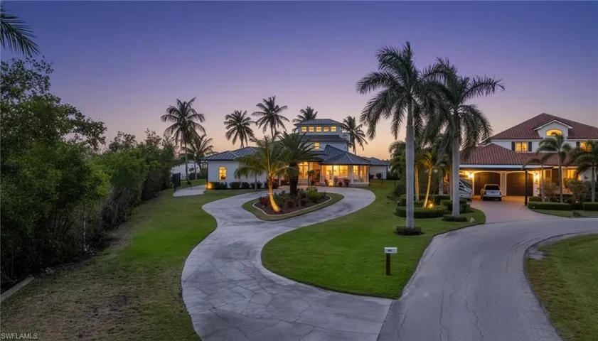 View of front facade with curved driveway, a front lawn, and a patio area