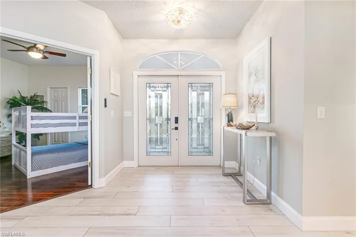 Foyer with light wood-style floors, a textured ceiling, a chandelier, french doors, and ceiling fan