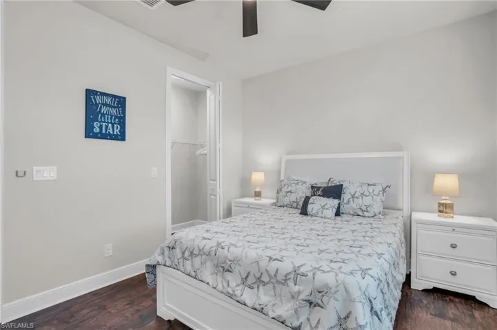 Bedroom with a walk in closet, dark hardwood / wood-style floors, a closet, and ceiling fan