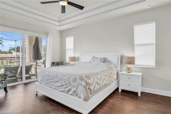 Bedroom featuring ornamental molding, dark hardwood / wood-style flooring, a tray ceiling, access to exterior, and ceiling fan