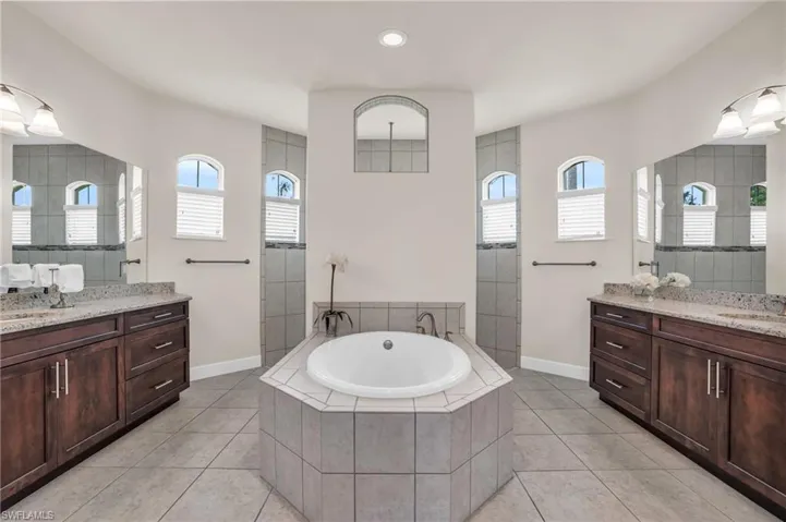 Bathroom with tile floors, a relaxing tiled bath, and double vanity