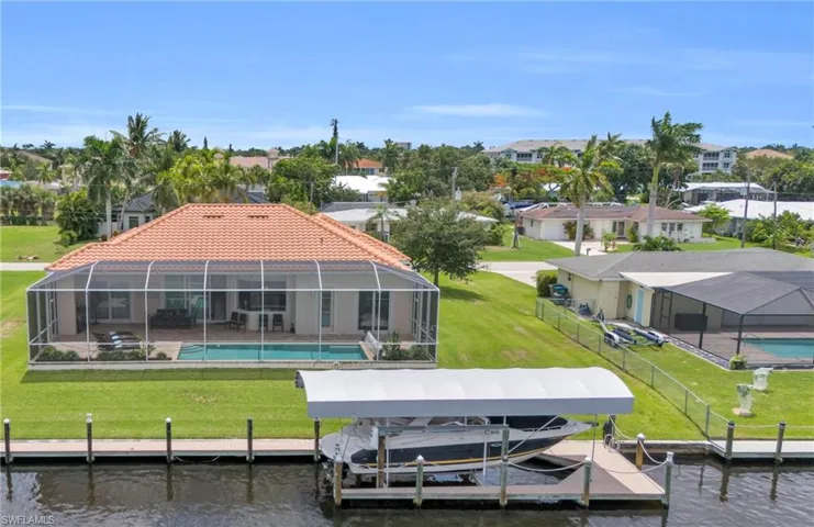 Rear view of house featuring glass enclosure, a water view, and a yard