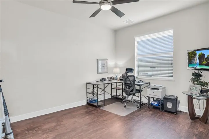Home office featuring ceiling fan and dark hardwood / wood-style floors