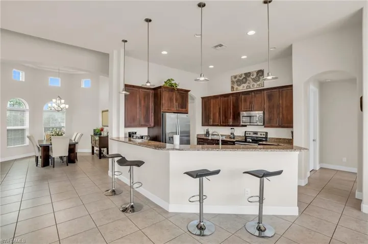 Kitchen featuring stainless steel appliances, light stone counters, decorative light fixtures, and a chandelier