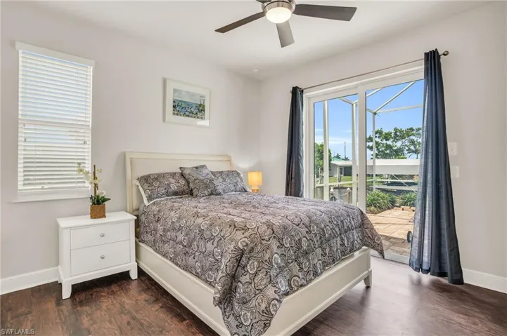 Bedroom featuring dark hardwood / wood-style floors, ceiling fan, multiple windows, and access to outside