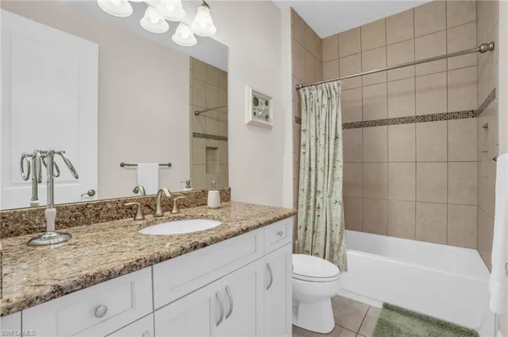 Full bathroom featuring tile flooring, shower / bath combo, toilet, and vanity