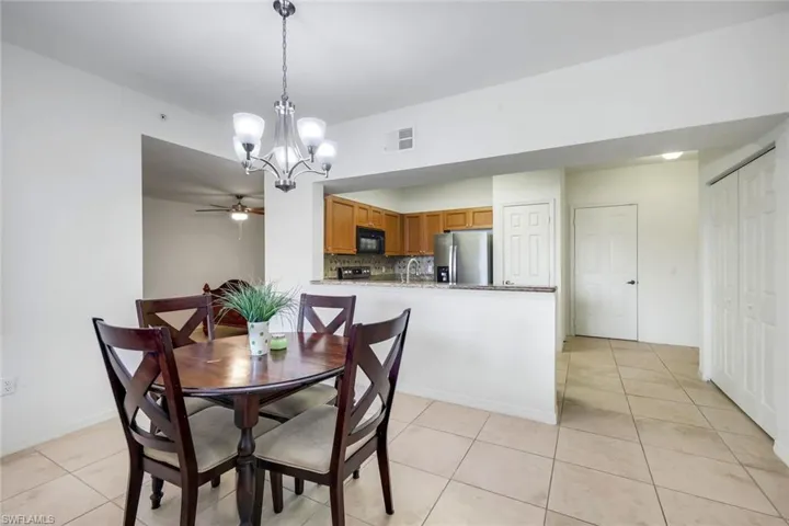 Dining area featuring a contemporary chandelier, tile flooring, and a breakfast bar with stone countertops