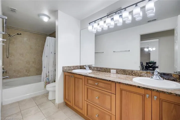 Bathroom featuring a double vanity with stone countertops, integrated oval sinks, and a full-width mirror