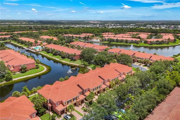 Aerial perspective showcasing a residential community with abundant waterways, mature landscaping, and uniform red tile roofs