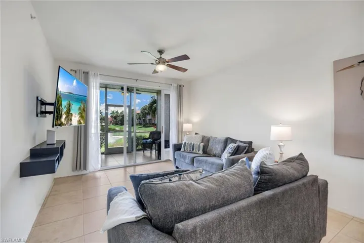Living area featuring tile flooring, a ceiling fan with integrated lighting, and a wall-mounted media shelf