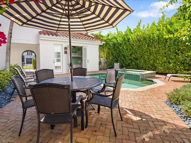 View of patio with outdoor dining area and a pool with connected hot tub