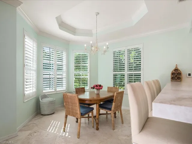 Dining room with suspended lighting, a raised ceiling, and ornamental molding