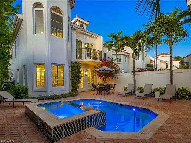 Back of property with a pool with connected hot tub, outdoor dining area, stucco siding, and a patio