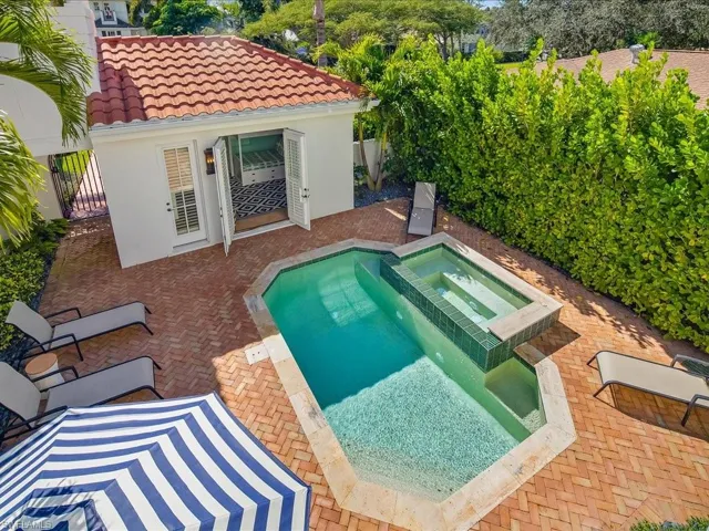 Relaxing pool / spa with a patio, an outdoor structure, and a storage structure