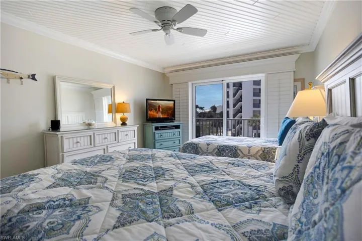Large guest bedroom with plantation shutters out to back balcony.