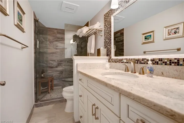 Guest bathroom with custom tile, heavy glass shower door, new vanity, lighting, and fixtures.