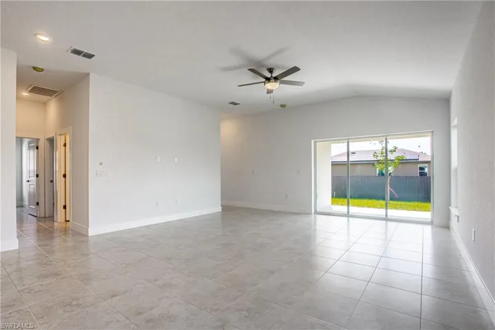 Spare room featuring lofted ceiling, baseboards, visible vents, and ceiling fan