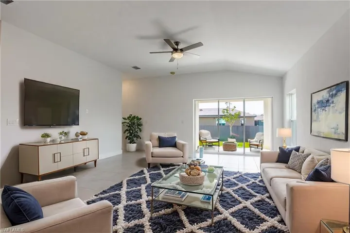 Living area with baseboards, lofted ceiling, a ceiling fan, and tile patterned flooring