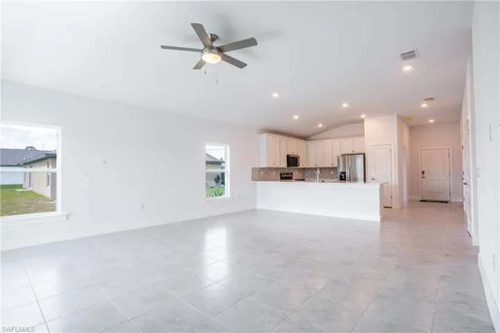Unfurnished living room featuring visible vents, a ceiling fan, recessed lighting, baseboards, and lofted ceiling