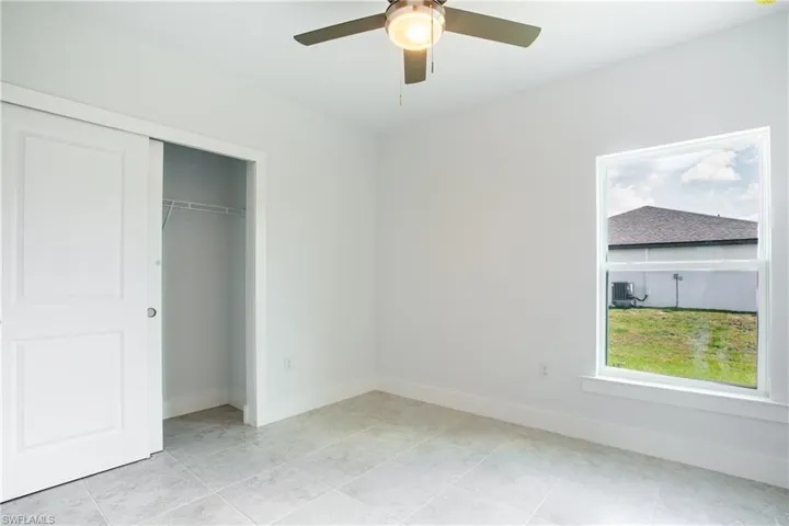 Unfurnished bedroom with light tile patterned flooring, baseboards, a closet, and ceiling fan