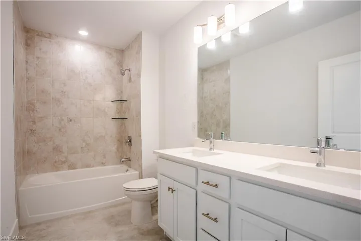 Full bath with double vanity, tub / shower combination, toilet, and a sink