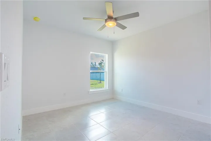 Spare room with light tile patterned flooring, ceiling fan, and baseboards