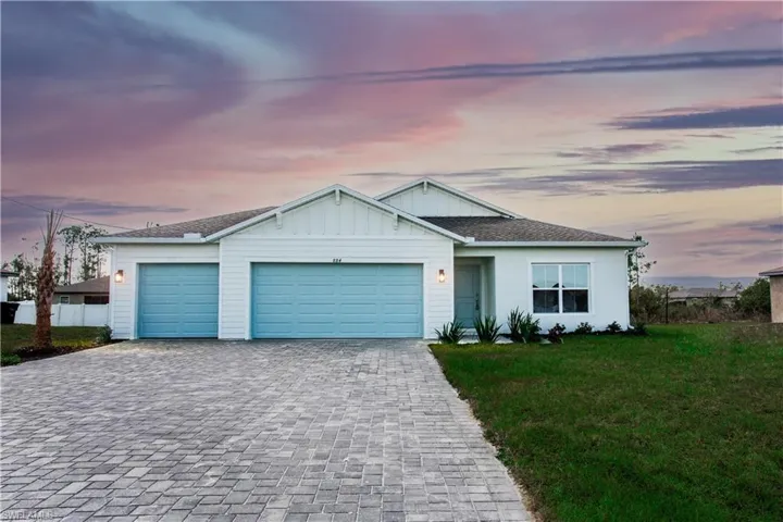 Single story home with decorative driveway, board and batten siding, a front yard, a shingled roof, and a garage