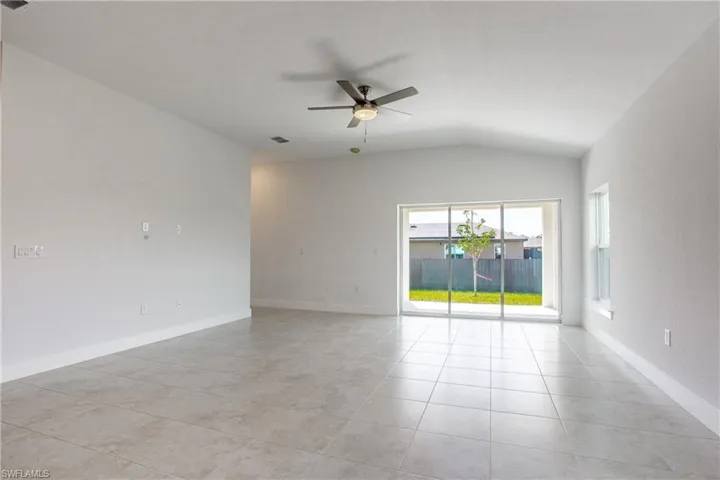 Unfurnished room featuring vaulted ceiling, light tile patterned floors, baseboards, and ceiling fan