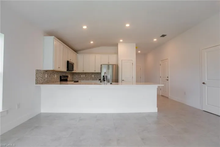 Kitchen featuring visible vents, appliances with stainless steel finishes, light countertops, and decorative backsplash