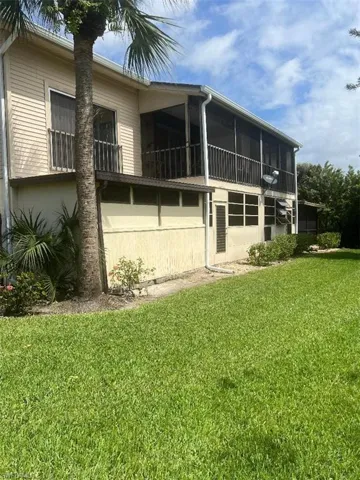 Rear view of property with a sunroom, a yard, and a balcony