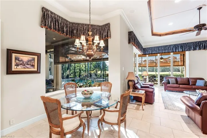Dining room featuring ceiling fan, healthy amount of natural light, ornamental molding, hanging lights, and tile patterned floors