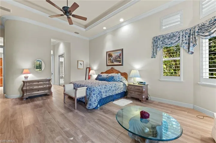 Bedroom featuring wood finished floors, crown molding, a ceiling fan, and a raised ceiling