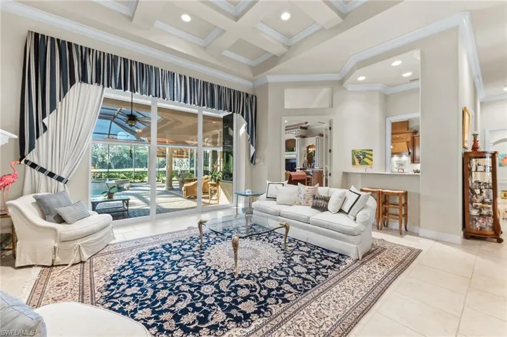 Living area with ceiling fan, a sunroom, coffered ceiling, crown molding, and recessed lighting