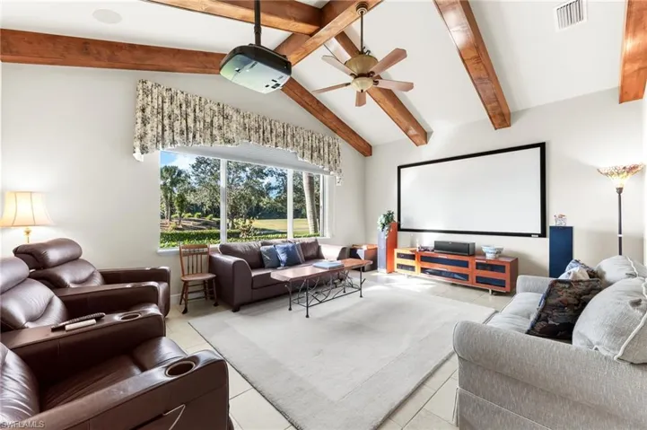 Home theater room featuring a ceiling fan, beam ceiling, and tile patterned flooring