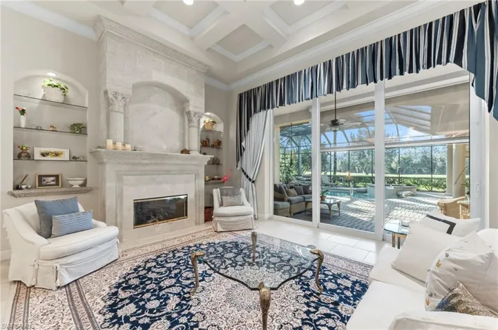 Living area featuring a sunroom, coffered ceiling, built in features, crown molding, and a ceiling fan