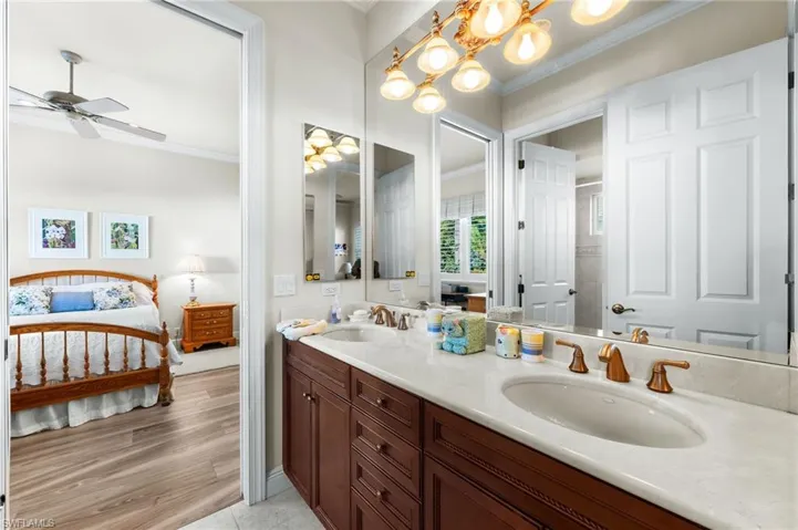 Ensuite bathroom with double vanity, ornamental molding, ceiling fan, and light tile patterned flooring