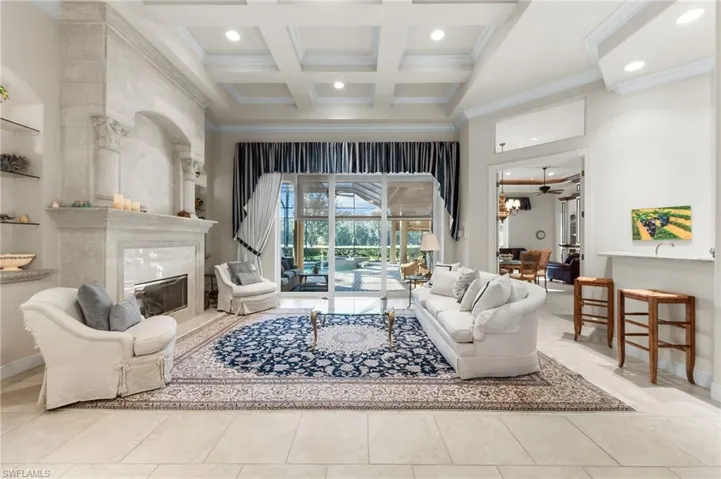 Living room with ornamental molding, coffered ceiling, a high end fireplace, and recessed lighting