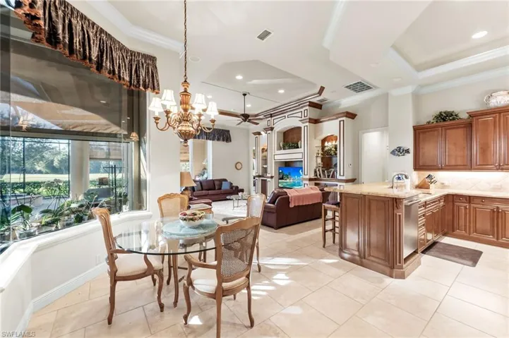 Dining room featuring ornamental molding, a tray ceiling, a chandelier, and light tile patterned flooring