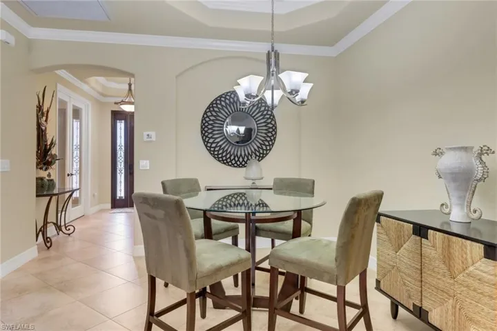 Dining room featuring arched walkways, light tile patterned floors, a chandelier, and crown molding
