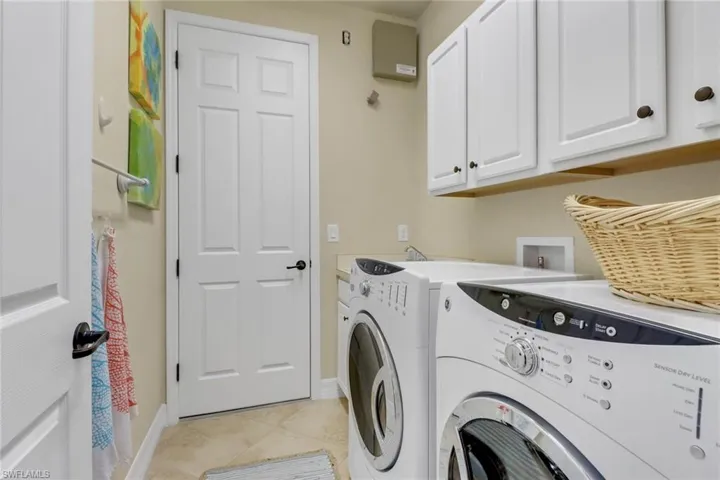 Washroom with cabinet space, separate washer and dryer, and light tile patterned flooring