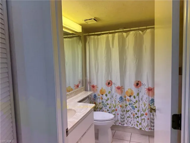 Full bath featuring vanity, light tile patterned floors, and a textured ceiling