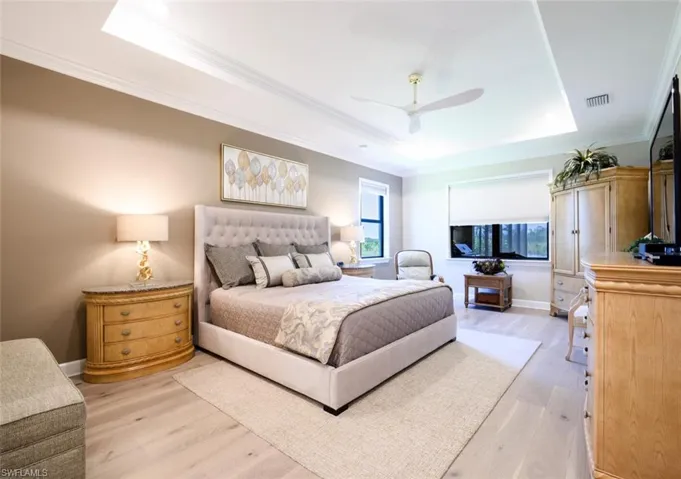 Bedroom featuring a tray ceiling, ceiling fan, light hardwood / wood-style floors, and ornamental molding