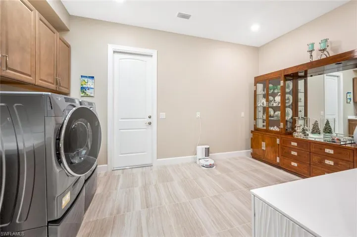 Washroom with washer and clothes dryer, cabinets, and light tile floors