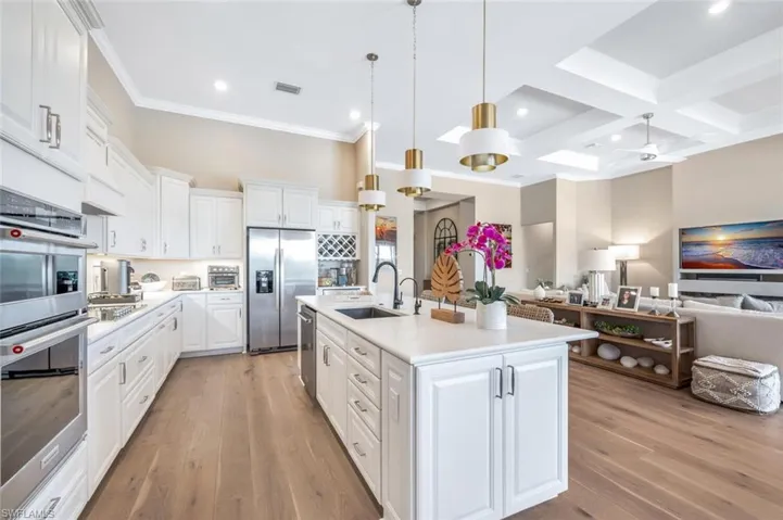 Kitchen with white cabinets, coffered ceiling, light hardwood / wood-style flooring, stainless steel appliances, and sink