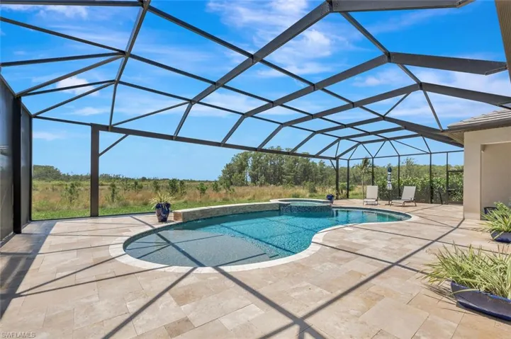 View of pool featuring a patio, glass enclosure, and an in ground hot tub